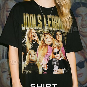 May include: Black unisex t-shirt featuring a graphic of a group of women with the text "JOOLS LEBROCK" in gold lettering. The shirt also has the word "SHIRT" above "Unisex" in white.