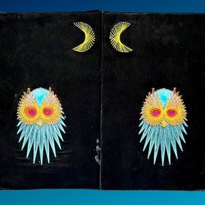 May include: A black rectangular string art piece featuring two identical owl designs and two yellow crescent moons. The owls are crafted with light blue, yellow, orange, and red threads, while the moons are created with yellow thread on a black background.