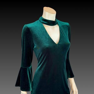May include: A dark green velvet dress with a keyhole neckline and bell sleeves.