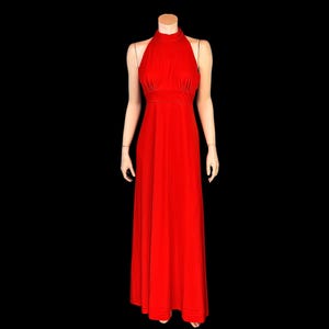 May include: A striking red halter-neck evening gown. The dress has a fitted bodice, a cinched waist, and a flowing, floor-length skirt. The gown is displayed on a mannequin against a black backdrop, emphasizing its elegant design.