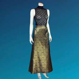 May include: A sleeveless black lace top and a floor-length gold and black patterned skirt are displayed on a mannequin. The skirt has a repeating geometric design. The mannequin is set against a blue background.