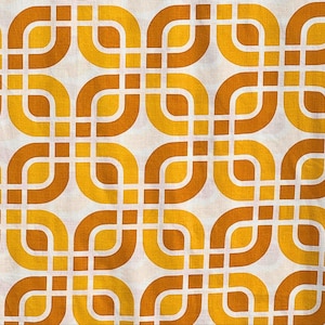 May include: A close-up of a fabric with a repeating geometric pattern. The design features interlocking, rounded shapes in shades of yellow and brown against a white background. The pattern has a retro, vintage aesthetic.