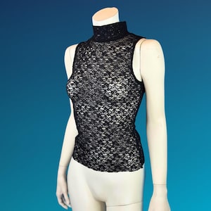 May include: Black sleeveless lace top with a high neckline. The intricate floral lace pattern covers the entire top. The top is displayed on a mannequin against a blue background.