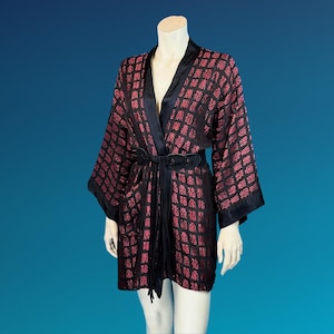 May include: A black and red patterned kimono-style robe with a black belt and trim. The robe has a geometric design and is displayed on a mannequin against a blue background.