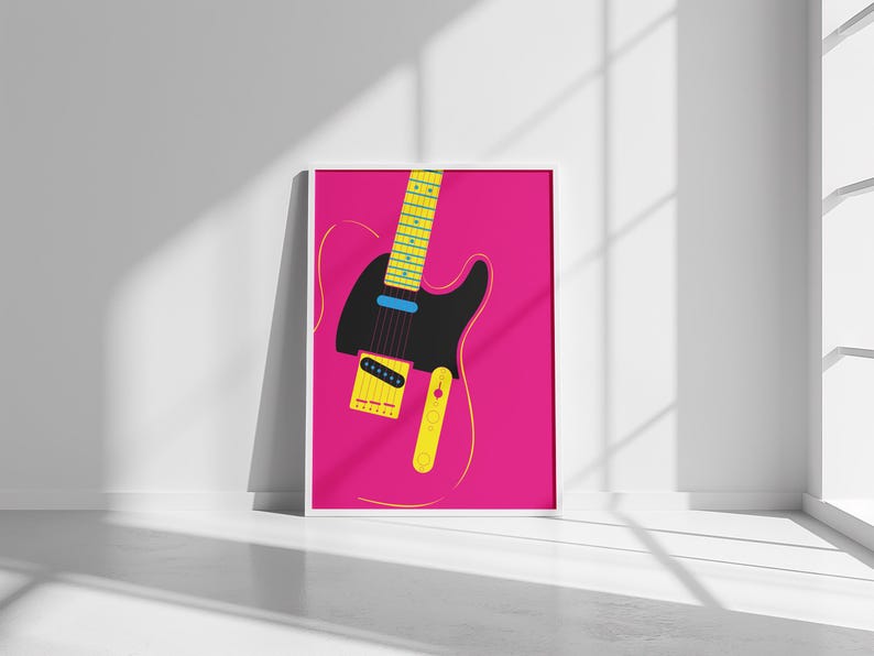 May include: A framed art print featuring a stylized electric guitar illustration. The guitar is black with yellow and blue accents, set against a vibrant pink background. The artwork is displayed in a white frame.