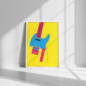 May include: A framed art print featuring a stylized electric guitar illustration. The guitar is depicted in bright colors: blue body, pink neck and accents, set against a yellow background. The artwork is displayed in a white frame.