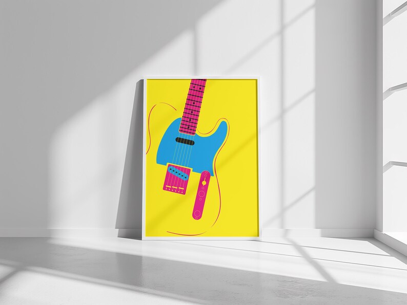 May include: A framed art print featuring a stylized electric guitar illustration. The guitar is depicted in bright colors: blue body, pink neck and accents, set against a yellow background. The artwork is displayed in a white frame.