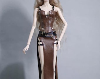 May include: A fashion doll wearing a brown faux leather outfit. The outfit includes a bustier top with straps and a long skirt with a high slit. The doll has long blonde hair and is posed against a gray background.