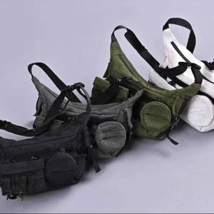 May include: Four sling bags in black, gray, olive green, and white. Each bag has a main compartment, a front pocket, and an adjustable black strap. The bags are made of a durable material and are designed to be worn across the body.