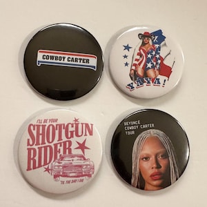 May include: Four round buttons with various designs. One button has "COWBOY CARTER" on a black background. Another features a woman in a cowboy hat with "YAYA!". A third says "SHOTGUN RIDER". The last button shows a woman with the text "BEYONCE COWBOY CARTER TOUR".