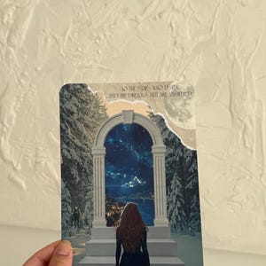 Könnte beinhalten: Eine rechteckige Karte mit einer Frau, die durch einen Torbogen in einen Sternenhimmel blickt. Auf der Karte steht der Text "TO THE STARS WHO LISTEN AND THE DREAMS THAT ARE ANSWERED" und "There you are. I've been looking for you."