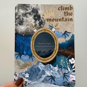 May include: A decorative card with a collage design, including a full moon, mountains, and a gold-framed oval. The text "climb the mountain" is visible. The card has a fantasy theme with blue and gold accents and other text.