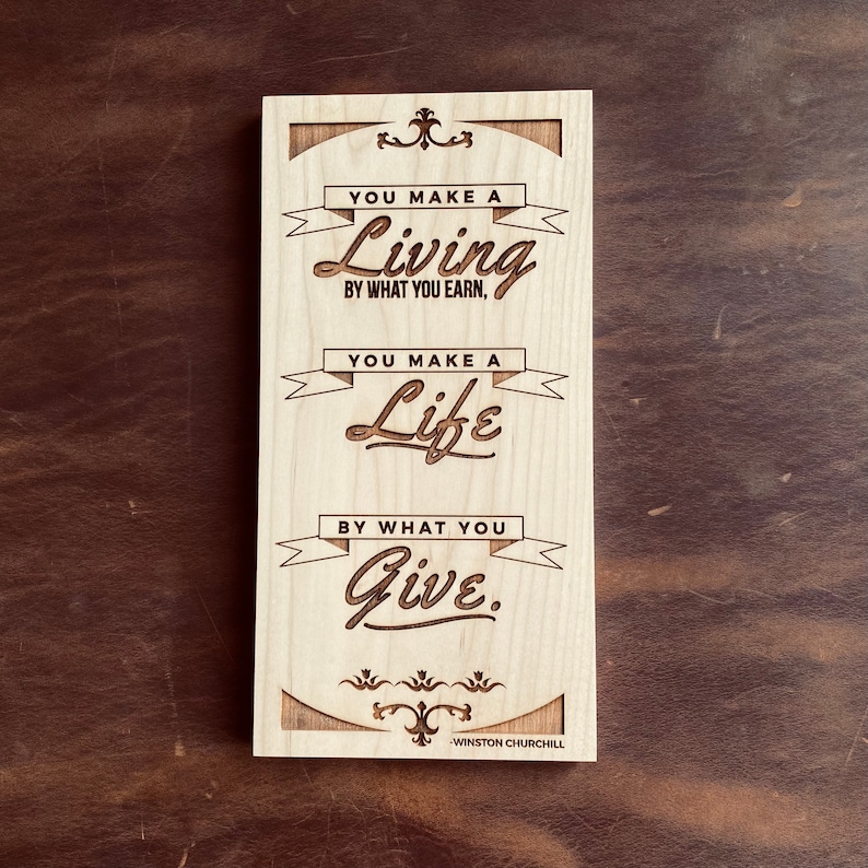 Op de afbeelding: Houten bord met een citaat van Winston Churchill: "Je verdient je brood met wat je verdient. Je maakt je leven met wat je geeft."