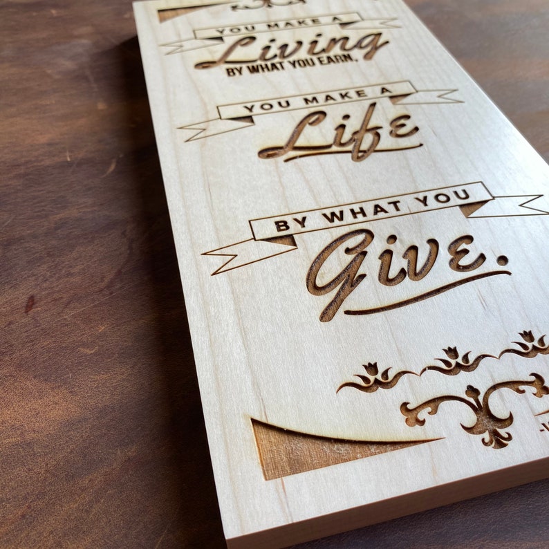 Op de afbeelding: Houten bord met de tekst "You make a living by what you earn, you make a life by what you give."