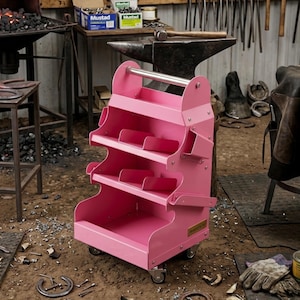 May include: A pink metal tool cart with three tiered shelves and a handle. The cart has wheels for easy movement and is designed for organizing tools. The cart is in a workshop setting.