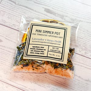 Puede incluir: Una bolsa de plástico transparente que contiene una mezcla para olla a fuego lento con lavanda seca, sal marina del Himalaya, trozos de canela, clavos, naranja y rodajas de limón. La etiqueta dice: MINI SIMMER POT, THE TIMELESS APOTHECARY.