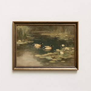 May include: A framed vintage painting depicts two ducks swimming in a pond with lily pads and flowers. The artwork features a muted color palette with shades of brown, green, and yellow, creating a serene and naturalistic scene.