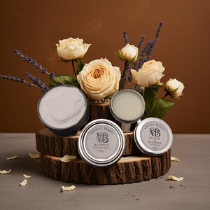 Puede incluir: Una exhibici&oacute;n de productos de belleza, incluyendo b&aacute;lsamo de sebo batido y b&aacute;lsamo labial de cera de abejas, presentados sobre una base de madera con rosas crema y ramitas de lavanda. Los productos est&aacute;n en latas plateadas.