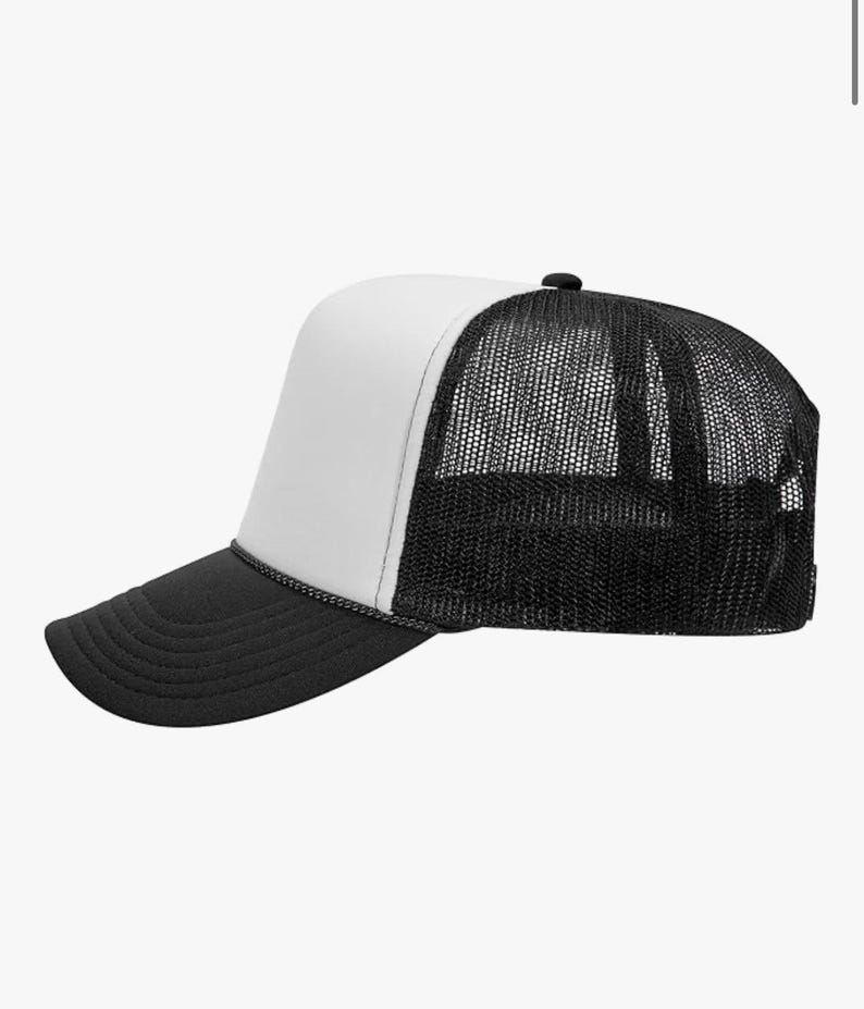 May include: A black and white trucker hat with a mesh back and a curved brim. The front panel is white, and the brim is black. A black rope detail separates the front panel from the brim.