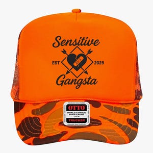 May include: Orange trucker hat with a camouflage pattern on the brim and mesh back. The front features the text "Sensitive Gangsta" with a heart and arrow design. Includes a "World Famous Foam Front" label.