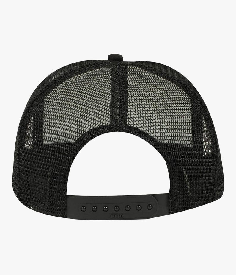 May include: Black trucker hat with a mesh back and a curved brim. The hat features a snapback closure for adjustable sizing. The crown is solid black, and the mesh back provides ventilation. A small button is on top of the crown.