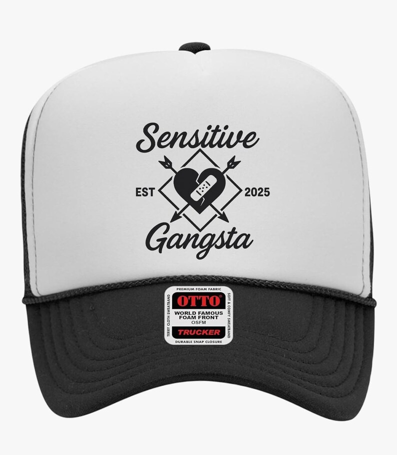 May include: A black and white trucker hat with the words "Sensitive Gangsta" and a heart graphic. The hat has a black brim and a white front panel with the text and graphic. The hat also has a black mesh back.
