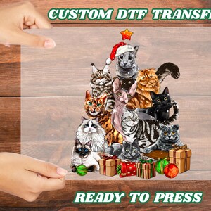 May include: A DTF transfer featuring a Christmas tree design made of various cat breeds. The cats are arranged in a tree shape, with a Santa hat on top. Presents and ornaments are at the base. The text "CUSTOM DTF TRANSFER" and "READY TO PRESS" are at the top and bottom.