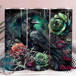 May include: A stainless steel tumbler featuring a detailed illustration of a raven perched amidst colorful flowers and foliage. The design includes the text "I have lived a thousand lives, lost in the pages of a book."