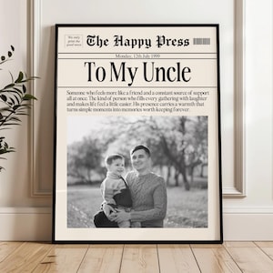 以下が含まれることがあります： 新聞風の「To My Uncle」と題された、額装された白黒プリント。プリントには「The Happy Press」というテキストと日付が含まれています。画像には、子供を抱いている男性が写っています。