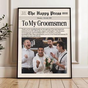 May include: A framed newspaper print titled "To My Groomsmen." The print features a photograph of a groom and his groomsmen celebrating. The headline reads "The Happy Press, Monday, 12th July 1999." The text expresses gratitude to the groomsmen.