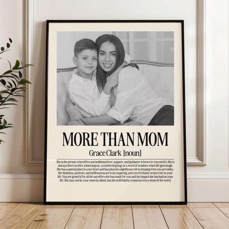 May include: Black and white framed print featuring a mother and child. The text "MORE THAN MOM" is displayed above the name "Grace Clark [noun]" and a description of a mother's role. A decorative piece for the home.