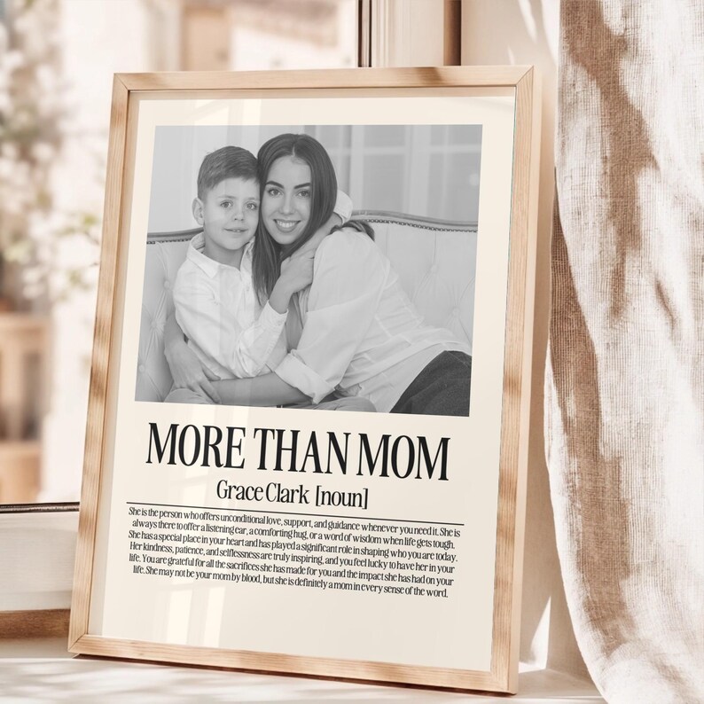 May include: A framed black and white print featuring a photograph of a mother and child. The text "MORE THAN MOM" is displayed prominently, with the name "Grace Clark" below. The print includes a definition of "mom".