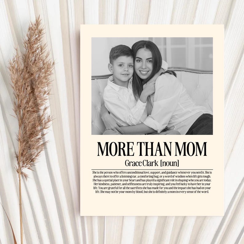 May include: A black and white print with the text "MORE THAN MOM" and a photo of a woman and child. The print includes a definition of the word "mom". The print is on a cream-colored background.
