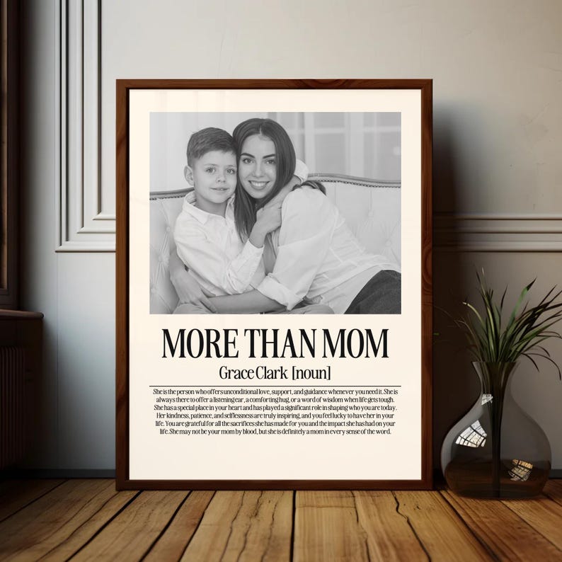 May include: A framed black and white print featuring a mother and child. The print has the text "MORE THAN MOM" and a definition of the word "mom". The frame is a dark brown color.