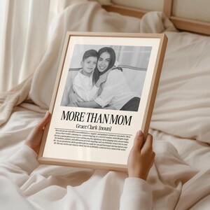 May include: A framed print with the text "MORE THAN MOM" and a black and white photo of a woman and child. The frame is light brown, and the print has a cream-colored background.