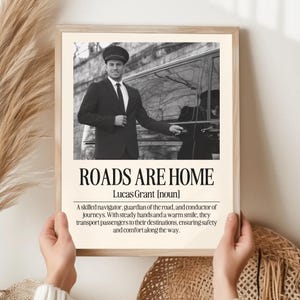 May include: Framed print with a black and white image of a chauffeur opening a car door. The text "ROADS ARE HOME" is displayed in bold letters, with the name "Lucas Grant" below. The print includes a definition of the term.