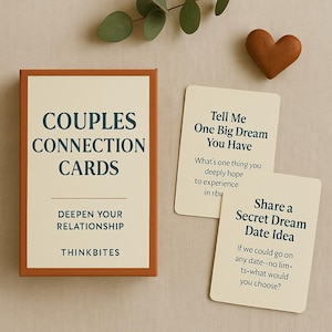 May include: A boxed set of "Couples Connection Cards" with the text "Deepen Your Relationship" and "Thinkbites". Two cards are displayed with prompts like "Tell Me One Big Dream You Have". A wooden heart is also present.