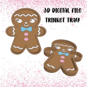 May include: A 3D digital file for a gingerbread man trinket tray. The gingerbread man has a brown body, white icing details, a blue bow tie, and pink buttons. The text "3D DIGITAL FILE TRINKET TRAY" is in black.