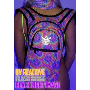 Op de afbeelding: Een UV-reactieve rugzak- en nekwarmer set met een geometrisch patroon in regenboogkleuren. De rugzak heeft een voorvak met een wit logo. De afbeelding bevat ook de tekst "UV REACTIVE FLASH IMAGE BLACK LIGHT IMAGE".