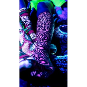 May include: A pair of neon pink and black swirl patterned socks. The socks are knee-high and have a unique, abstract design. The image is taken in a dark setting with neon accents, highlighting the vibrant colors and patterns of the socks.