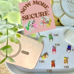 May include: A collection of colorful gnome charms with various patterns and designs, displayed on a white tray. The image includes a phone, a decorative tray, and text that reads "Now More Secure."