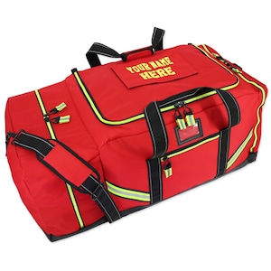 May include: A large red duffel bag with black accents and yellow zippers. The bag has a shoulder strap and handles. The text "YOUR NAME HERE" is printed in yellow on the top of the bag. Reflective yellow stripes are visible.