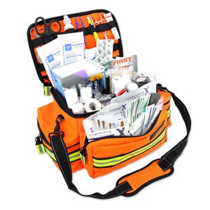 Könnte beinhalten: Geöffnete orangefarbene Erste-Hilfe-Tasche mit schwarzem Schultergurt. Das Set ist mit medizinischen Materialien gefüllt, darunter Bandagen, Gaze und Scheren. Das Set hat reflektierende Streifen und einen schwarzen Reißverschluss.