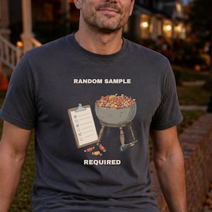 May include: A charcoal gray short-sleeve t-shirt featuring a graphic of a clipboard and a bowl filled with colorful candy. The text "RANDOM SAMPLE" is printed above the graphic, and "REQUIRED" is printed below it in white capital letters.