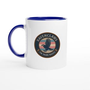 Pode incluir: Caneca de cerâmica branca com interior e alça azuis. A caneca apresenta um design circular com um corvo azul, o texto "RAVENCLAWS" e "FOR TRANS RIGHTS" em estilo vintage.