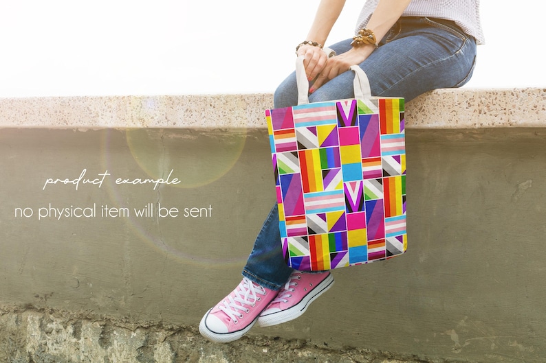 Puede incluir: Un bolso tote colorido con un dise&ntilde;o geom&eacute;trico que incluye los colores de la bandera del orgullo transg&eacute;nero. El bolso, con asas blancas, lo sostiene una persona que lleva vaqueros y zapatillas rosas. El texto de la imagen dice: "product example, no physical item will be sent."