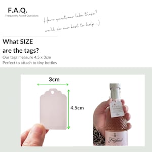 May include: A white gift tag with a scalloped edge and a hole for string. The tag measures 4.5 inches by 3 inches. The tag is being held by a hand, and a small bottle of sparkling wine is in the background.