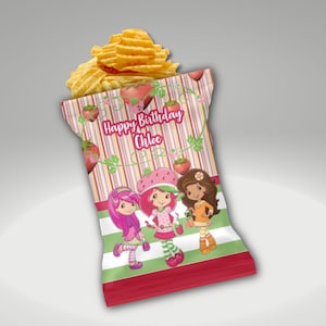 Op de afbeelding: Een zakje chips met een aangepast ontwerp. De zak bevat drie cartoonmeisjes, aardbeien en de tekst "Happy Birthday Chloe" op een gestreepte achtergrond met een rode basis.