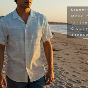 Pu&ograve; includere: Una camicia a maniche corte di colore chiaro con un motivo a tema spiaggia, con conchiglie e coralli rosa. La camicia &egrave; indossata da una persona su una spiaggia sabbiosa. Il testo dice "Stunning Mockups for Every Clothing Product."