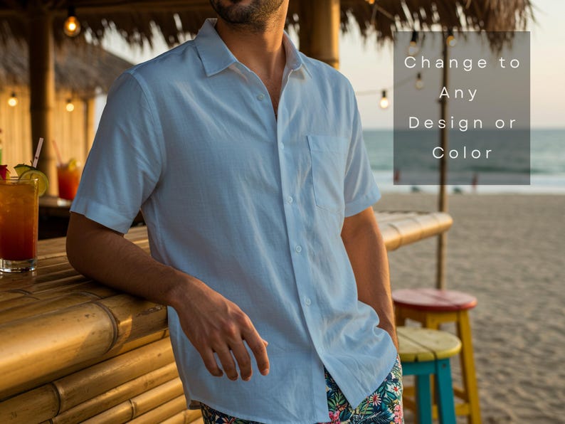 May include: A light blue short-sleeved button-down shirt with a pocket. The shirt is worn by a person leaning on a bamboo bar. The text on the image says "Change to Any Design or Color". The background includes a beach and cocktails.